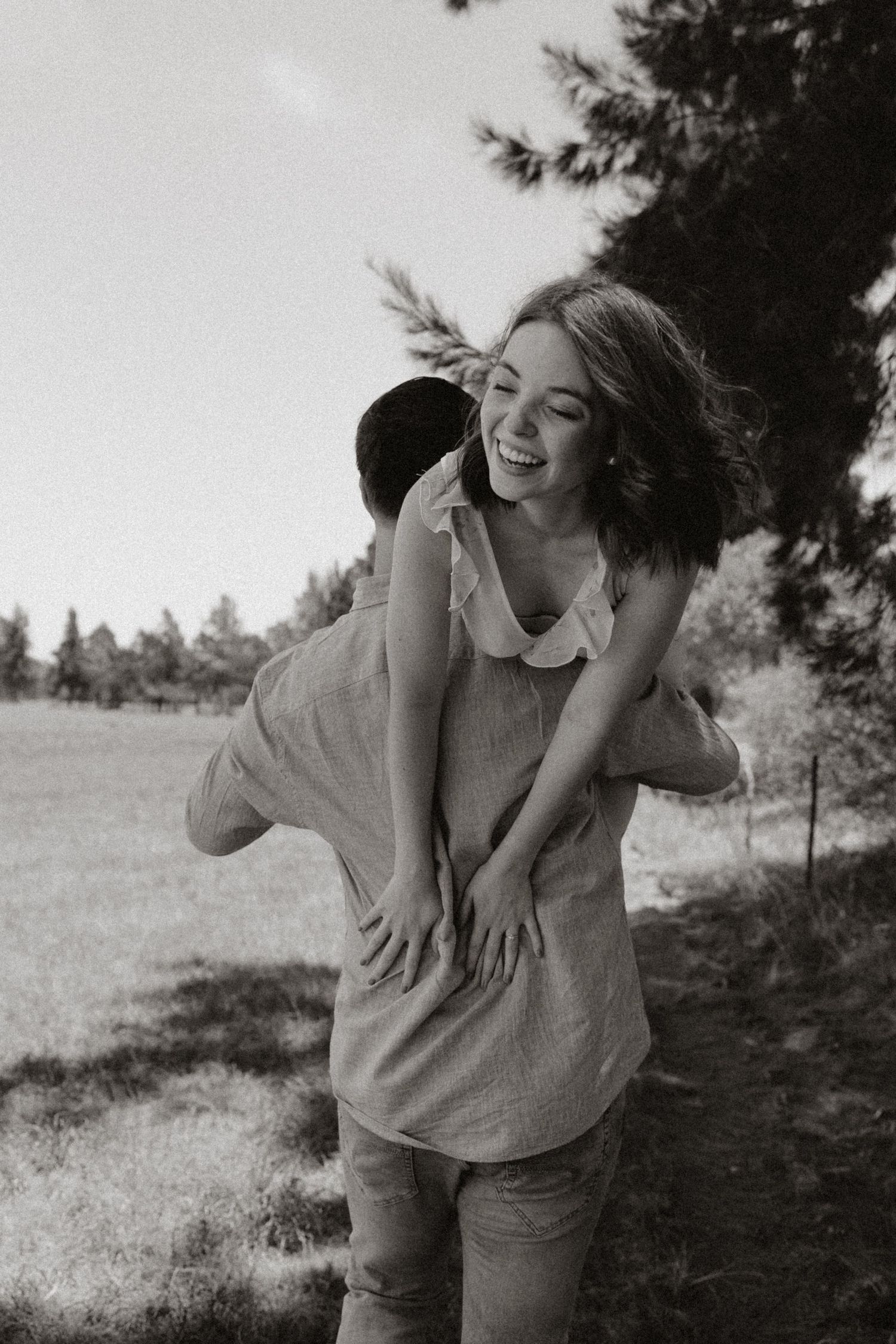 A joyful piggyback ride moment captured in black and white photography outdoors.