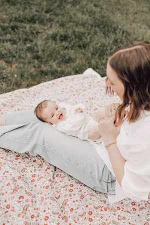 A tender moment captured on a floral blanket outdoors showing connection and joy between two people on a sunny day.