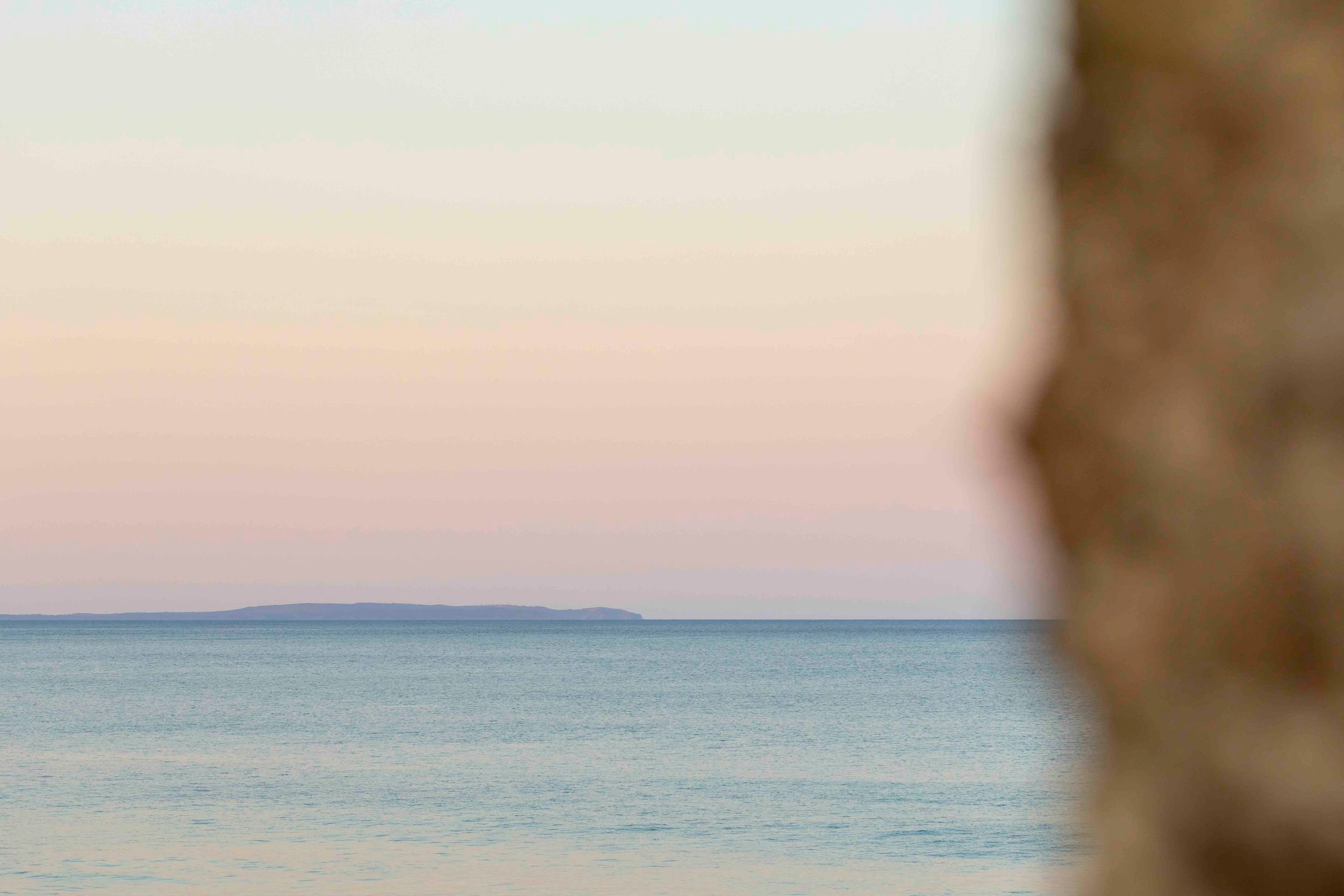 Serene ocean view at dusk with calm waters stretching to distant shoreline.