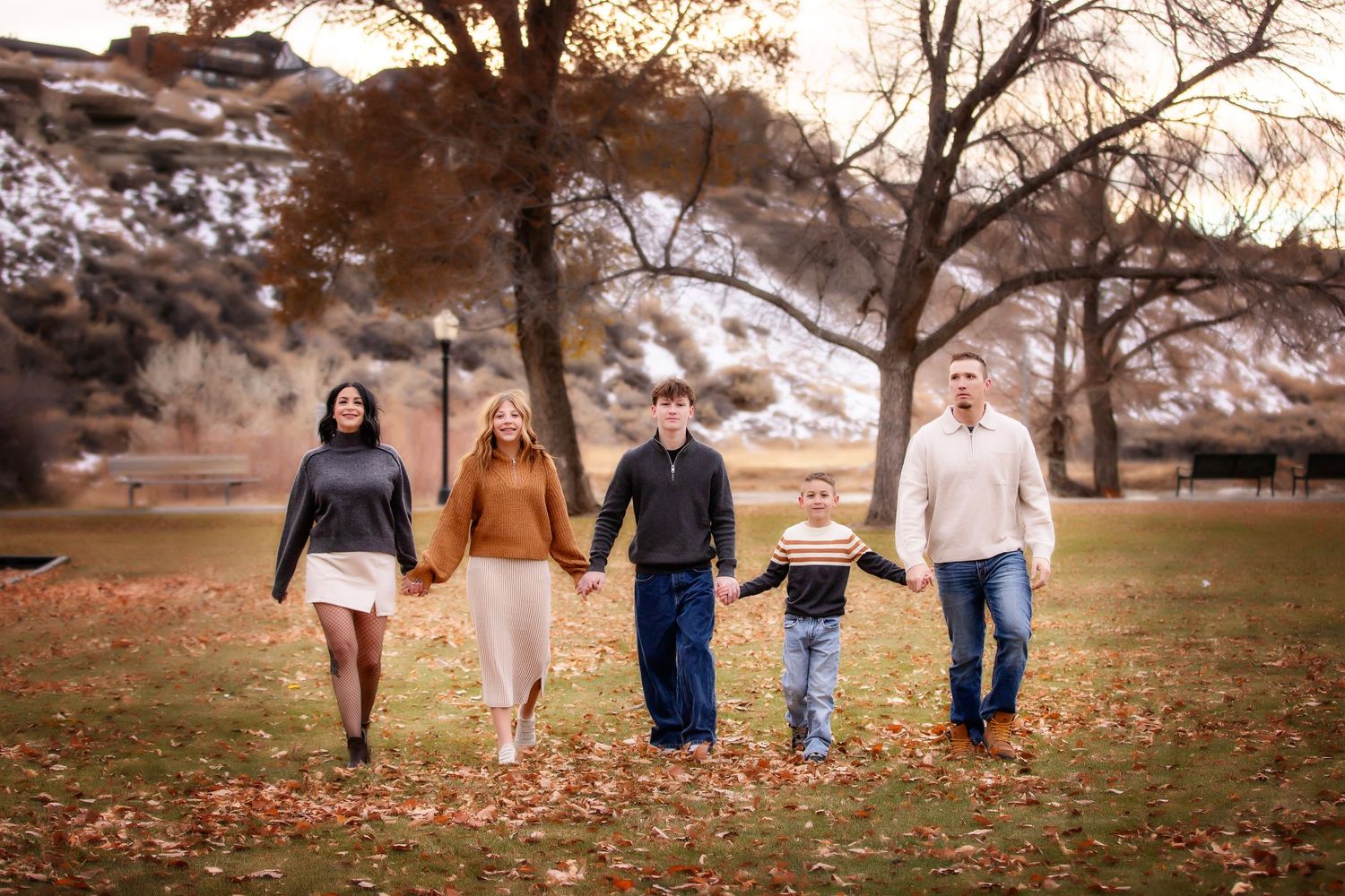 People running through golden field toward couple during autumn photo session.