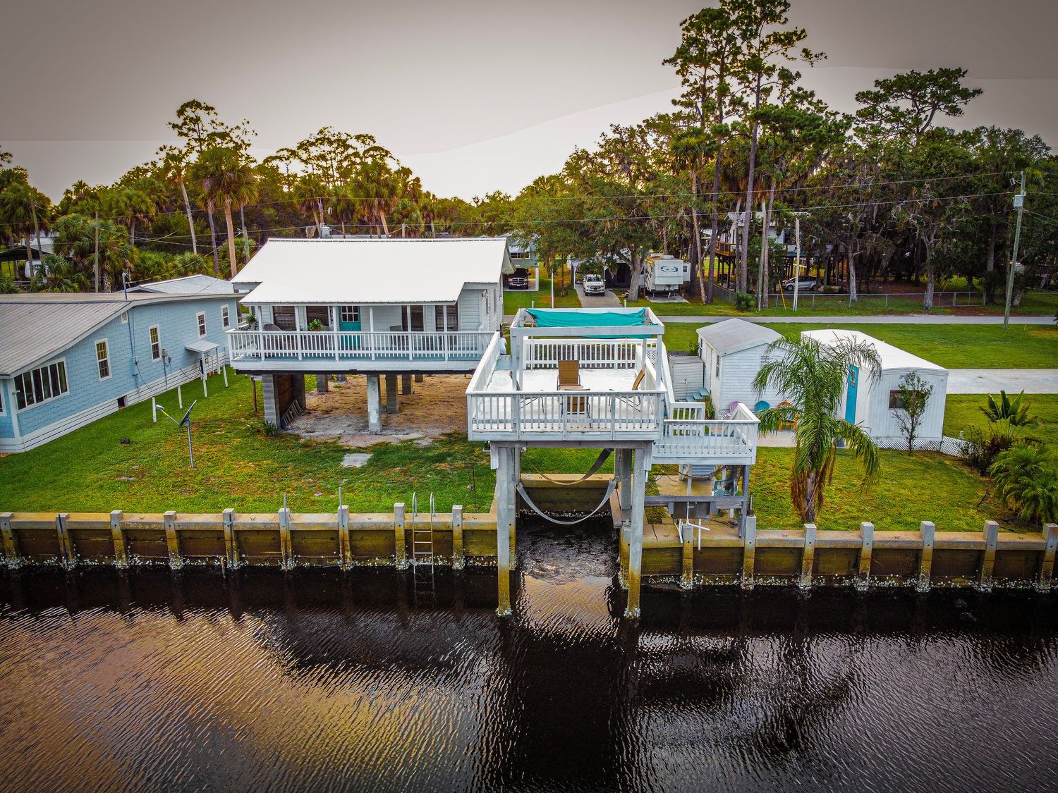 Aerial view of waterfront property with swimming pool and private boat dock on canal.