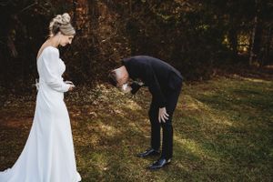 Couple shares a romantic first look moment outside a rustic wooden barn on their wedding day.