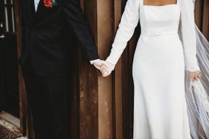 Bride and groom exchange gifts during their first look at a rustic outdoor wedding venue.