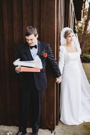 Groom presents a wrapped gift to his bride during their first look wedding moment.