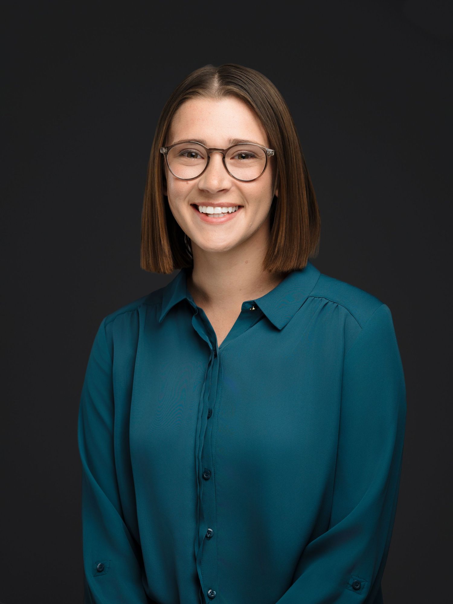 Professional headshot series in teal button-up shirt against dark background showing warm, approachable expressions.