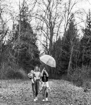A mother and her children with an umbrella in the woods