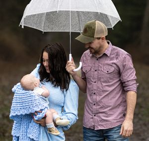 Mom and dad with baby under an umbrella