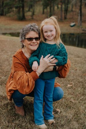 A warm autumn portrait by a lake with a teal sweater and rusty orange top creating a cozy outdoor scene.