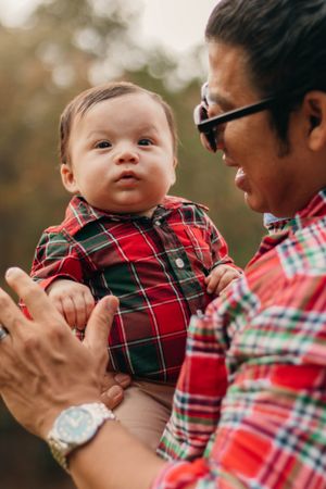 Close-up of parent and baby in coordinating plaid outfits sharing a joyful outdoor moment.