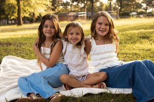 Family group lying in grass during golden hour sunlight wearing coordinated white and denim outfits.
