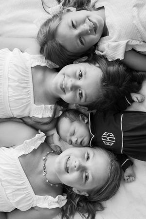 Black and white portrait series of people lying down together in white clothing.