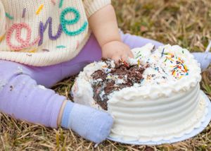 Close up of chocolate cake interior revealed through messy white frosting with sprinkles.