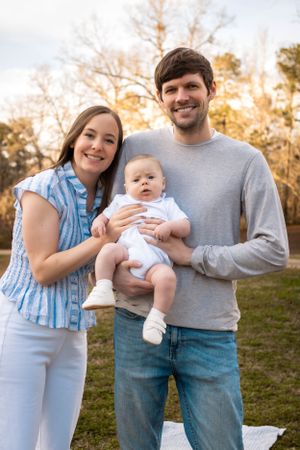 Happy family posing together outdoors in casual clothing during sunset.