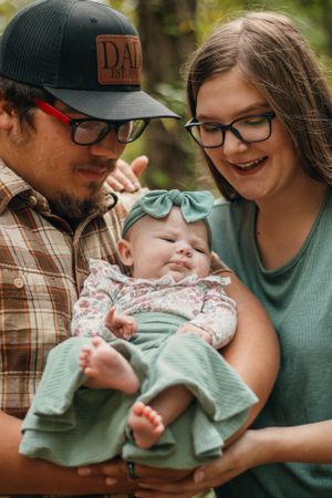 A couple gazes lovingly at their sleeping baby wearing mint and floral clothing.