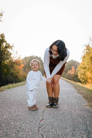 A touching moment between parent and child walking together on a gravel path at sunset.