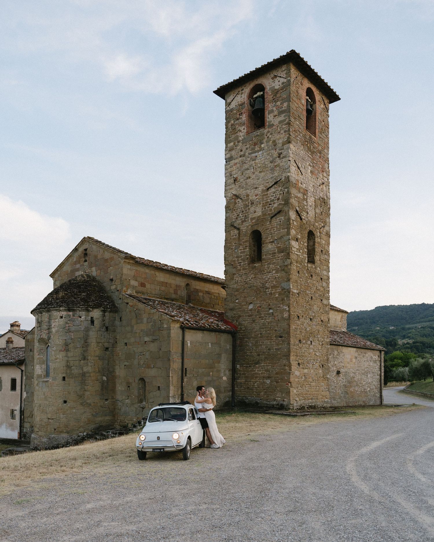 Historic stone church buildings with bell towers along a winding countryside road.