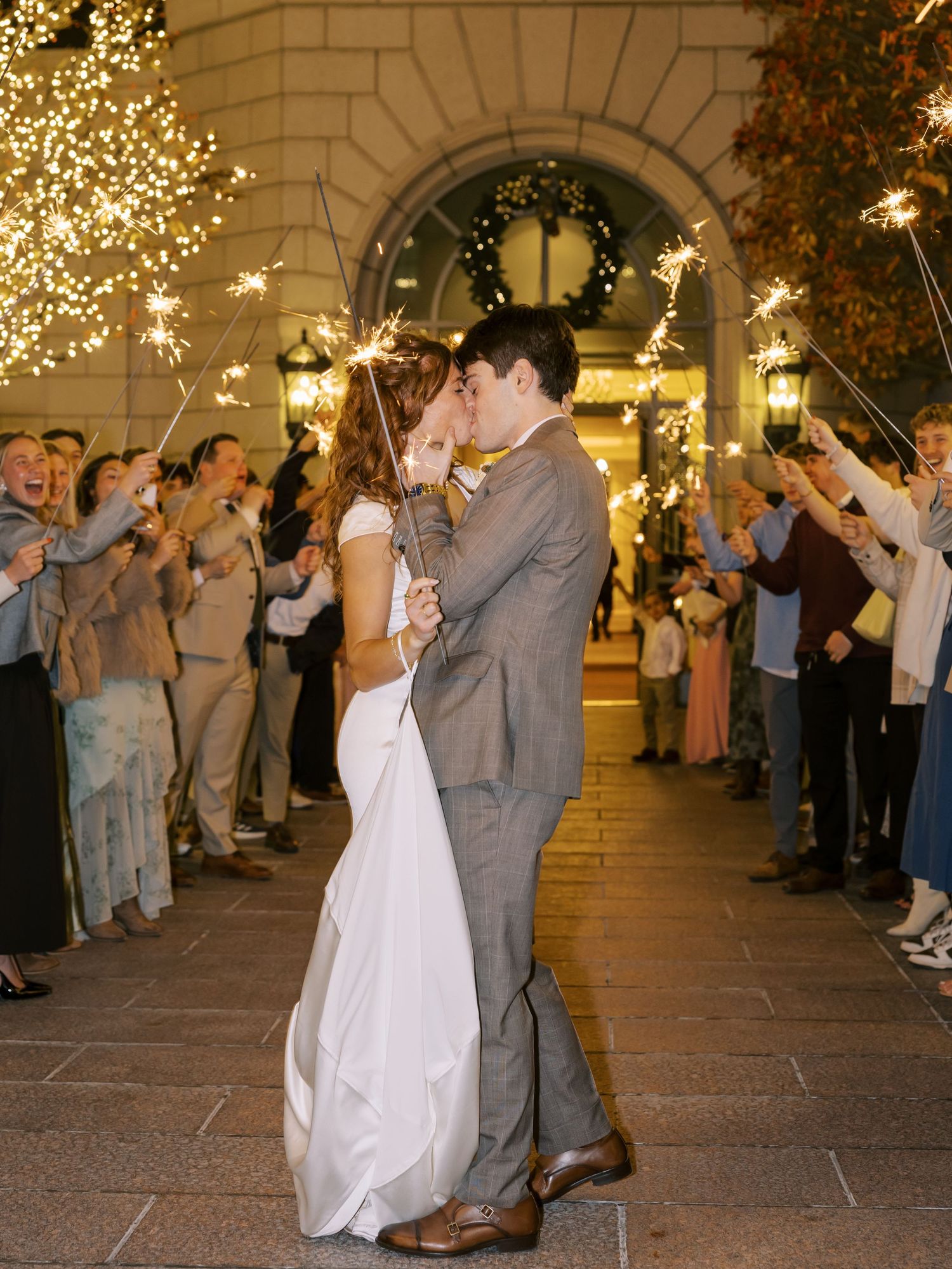 Couple shares first dance under twinkling lights at outdoor evening reception.