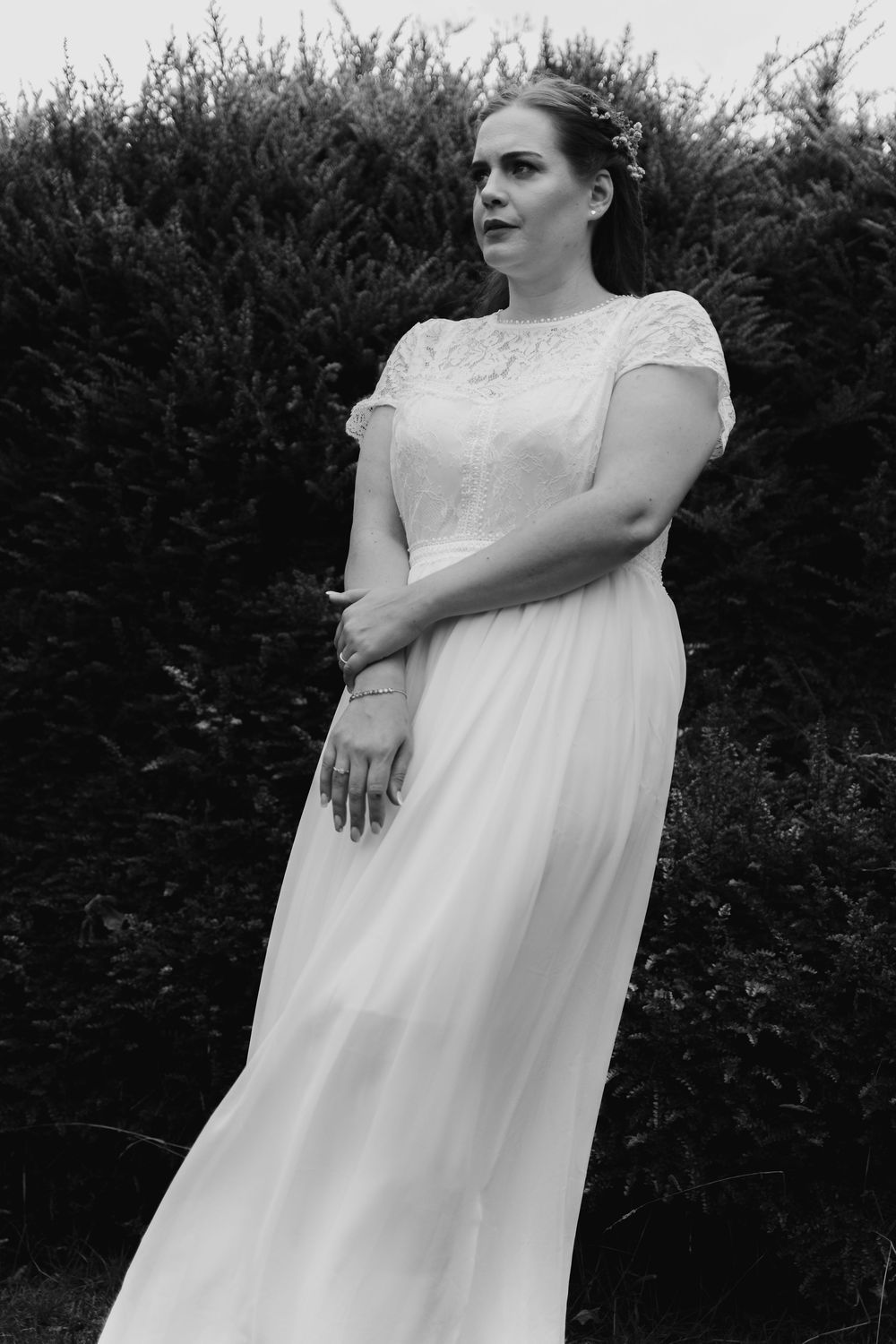 A series of artistic black and white wedding photos showing a bride in a flowing white dress against hedges.
