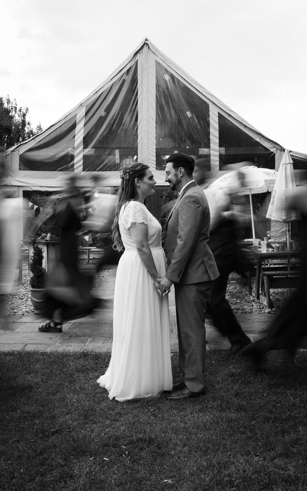 Black and white sequence of wedding guests dancing and moving around a tent at an outdoor reception.