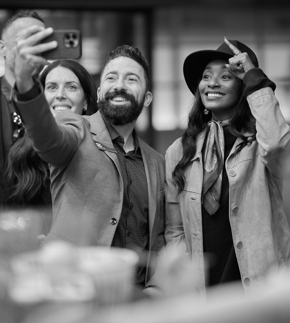 Black and white photo of people taking a selfie at a social gathering. Zillow Rentals event on rooftop