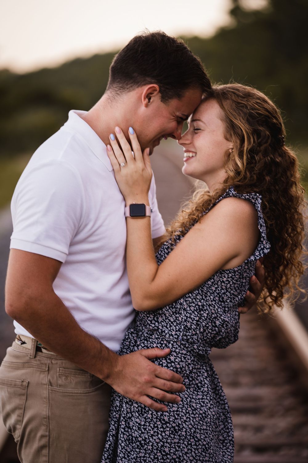 A romantic couple embraces intimately during sunset in a meadow.