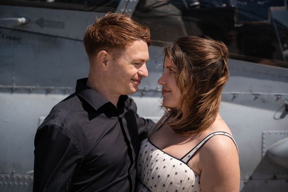 Couple sharing intimate moment near aircraft in sunlight.