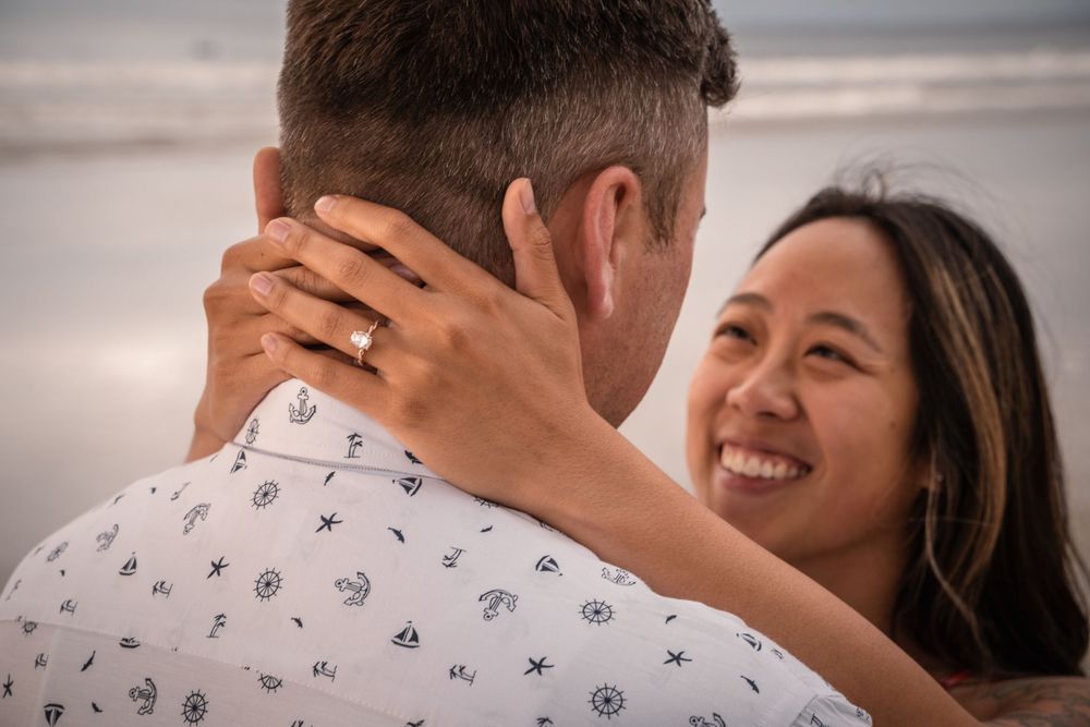 A tender romantic moment captured at sunset with the ocean in the background.