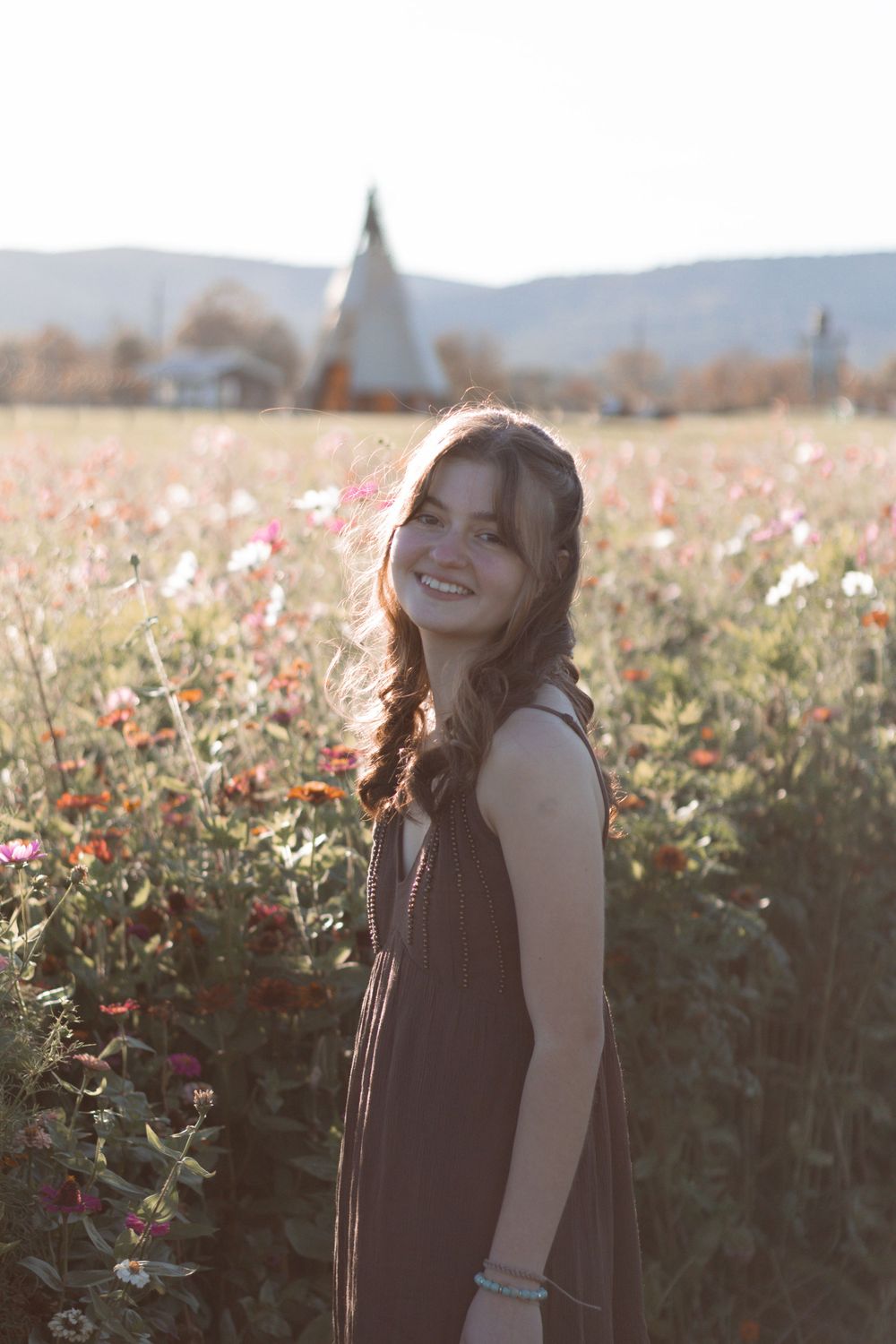 Artistic portraits captured in a flower field during sunset with mountains in the distance.