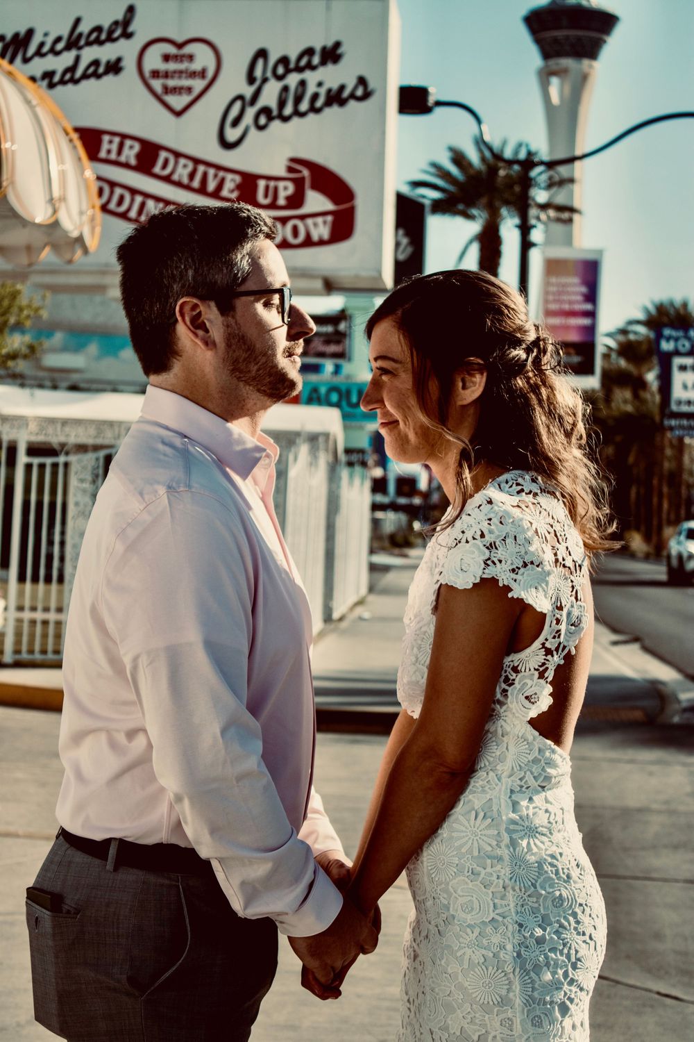 Newlywed couple holding hands and smiling at each other outside a Las Vegas wedding chapel on the Strip.