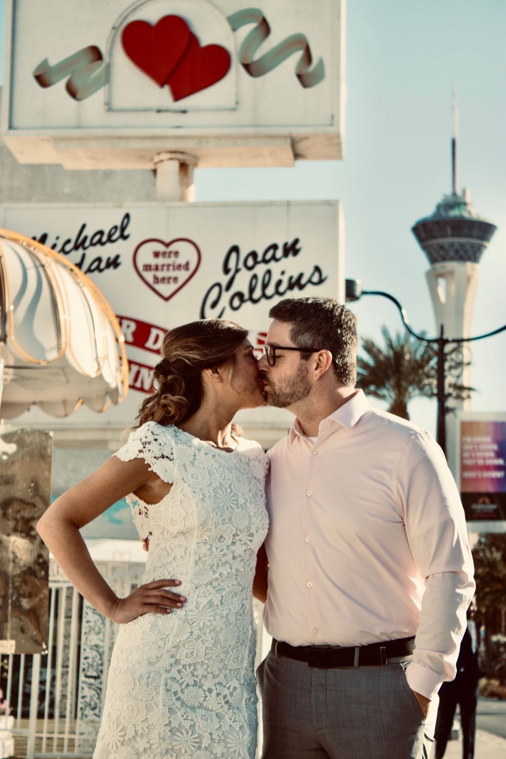 Couple kissing in front of A Little White Chapel sign in Las Vegas on their wedding day.