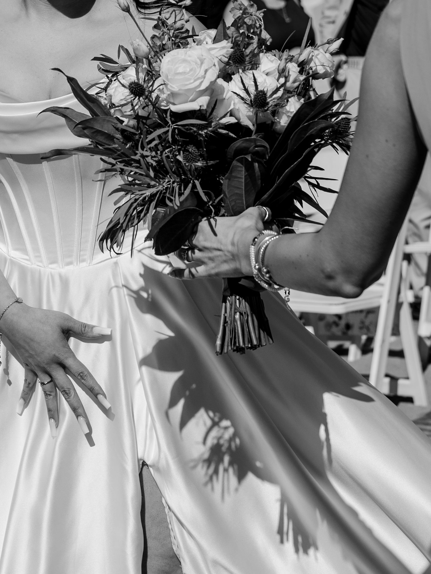 A romantic wedding moment with a bouquet of pink flowers being held during an outdoor ceremony.