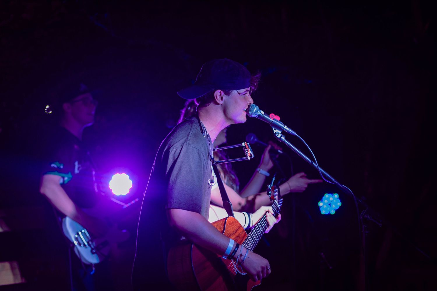 A musician performs on stage with blue and purple lighting effects.
