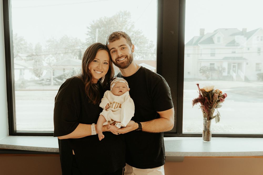Family moment in bright hospital room with window view.