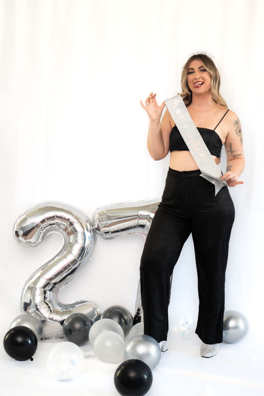 A festive portrait session with silver number balloons and black attire against a white backdrop.