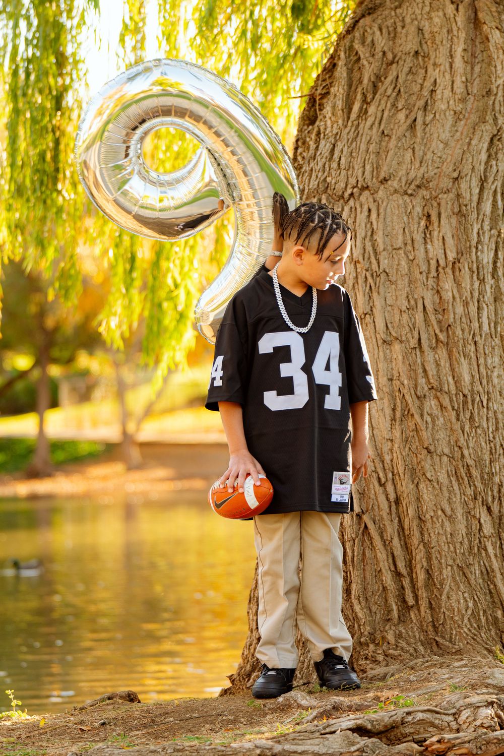 A sequence of photos near a willow tree by a pond with a football.