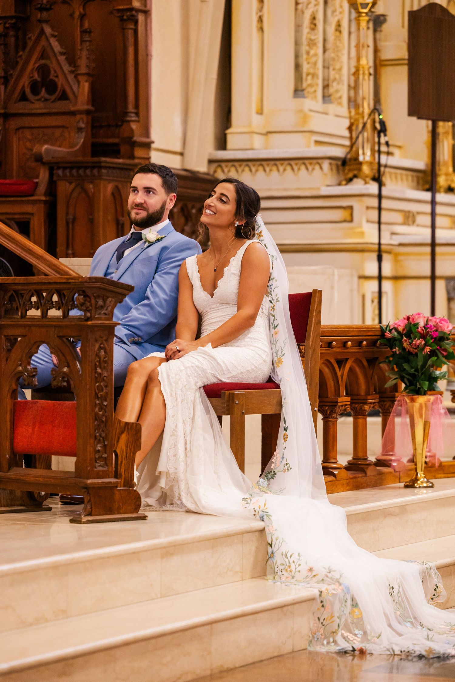 Couple seated on church altar steps during wedding ceremony.