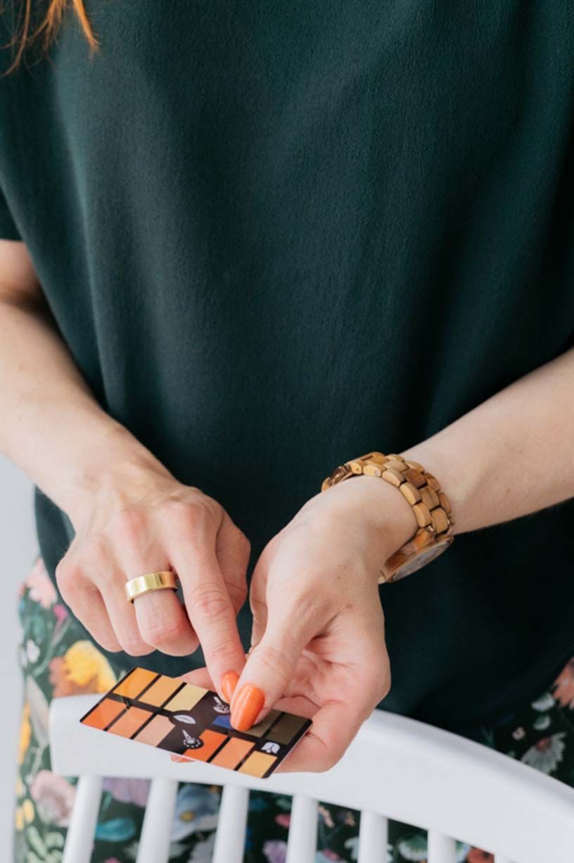 Hands holding color swatches against a dark background while arranging them in a sequence.