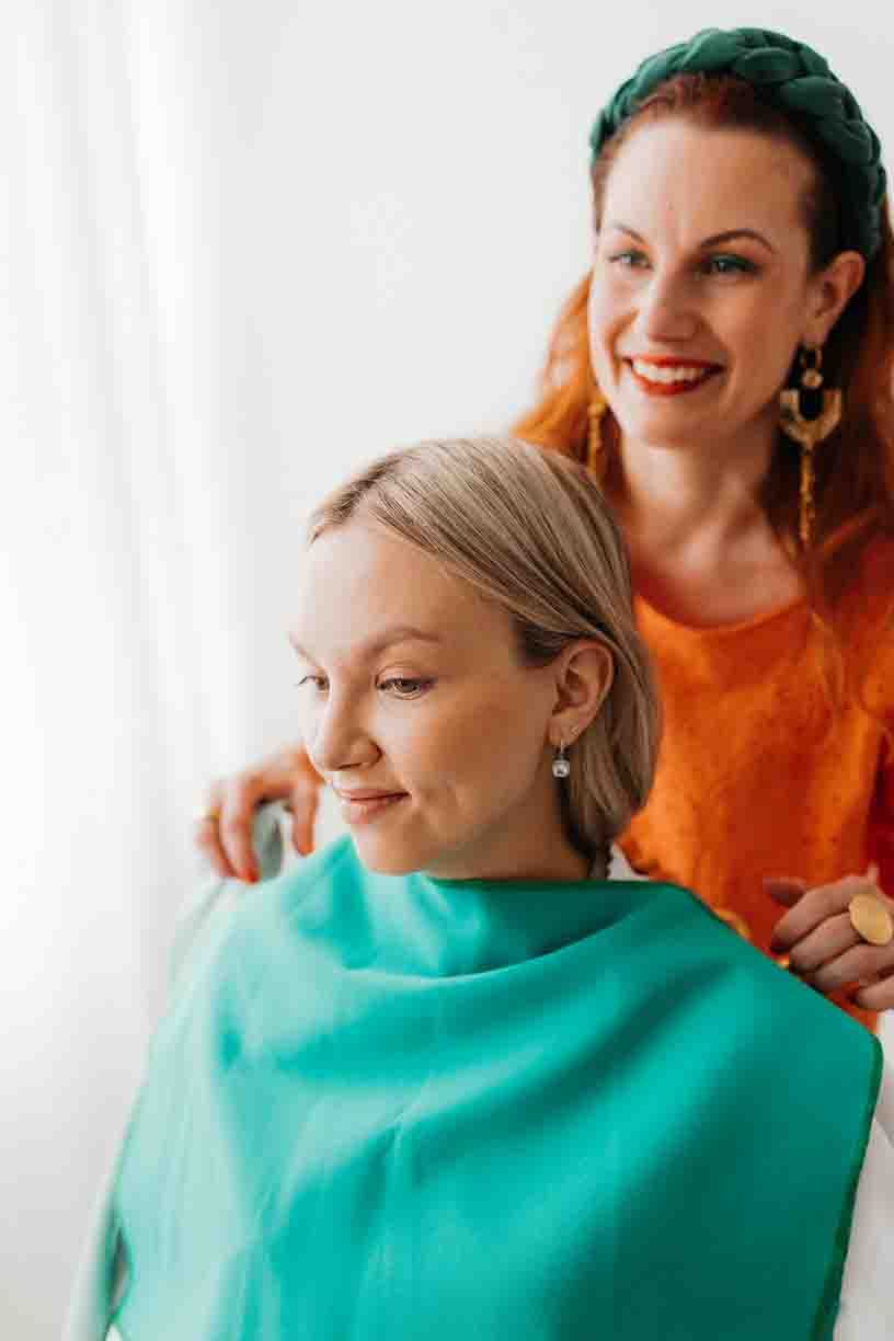 Two women in bright orange and turquoise clothing smile together during a casual photo session.