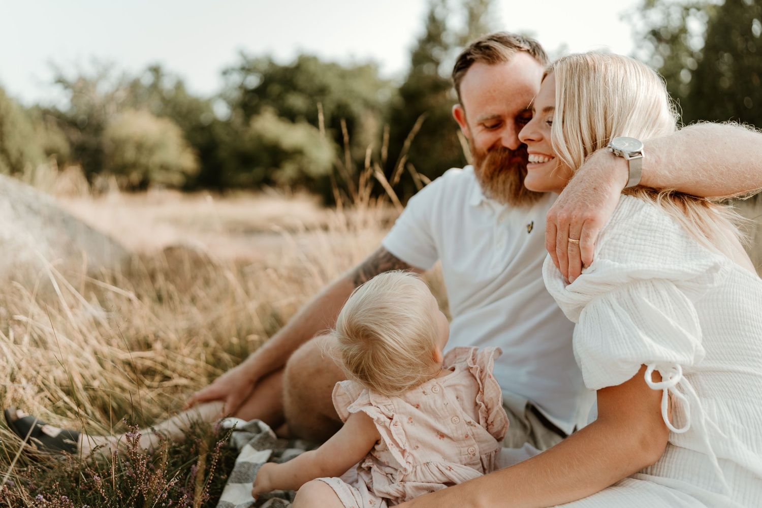 Family enjoying tender moment together in golden sunlit field.