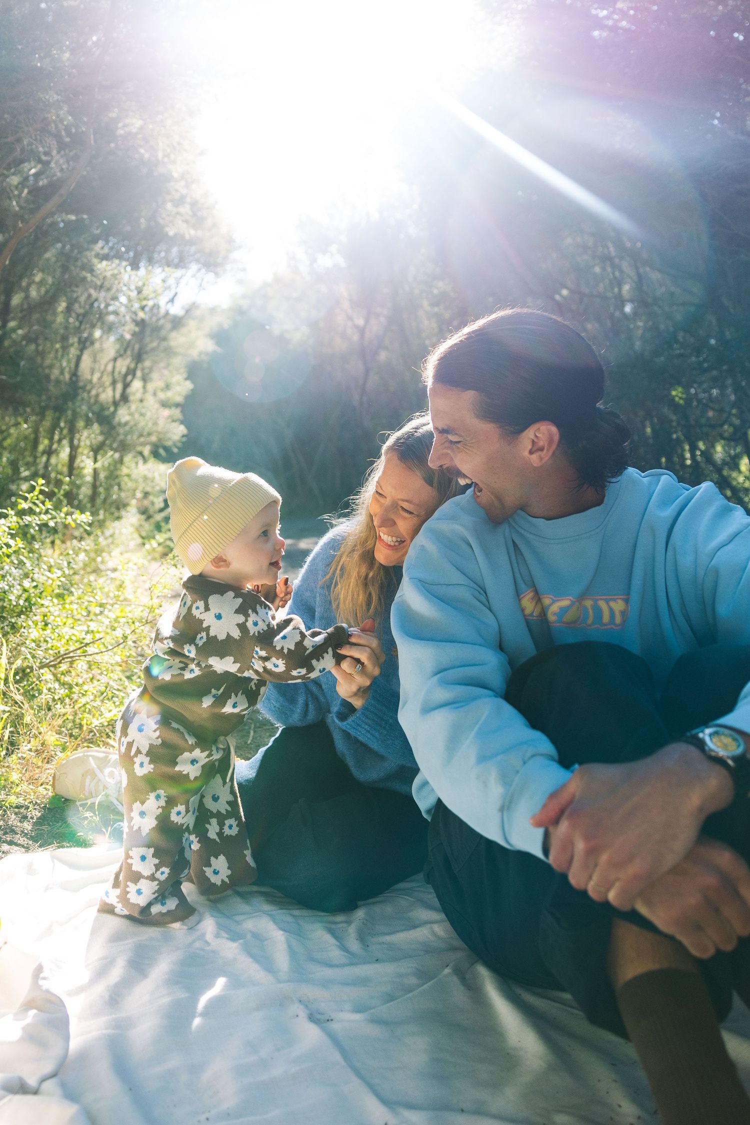 A warm candid family photo with the winter sun streaming in on a beautiful family of three.