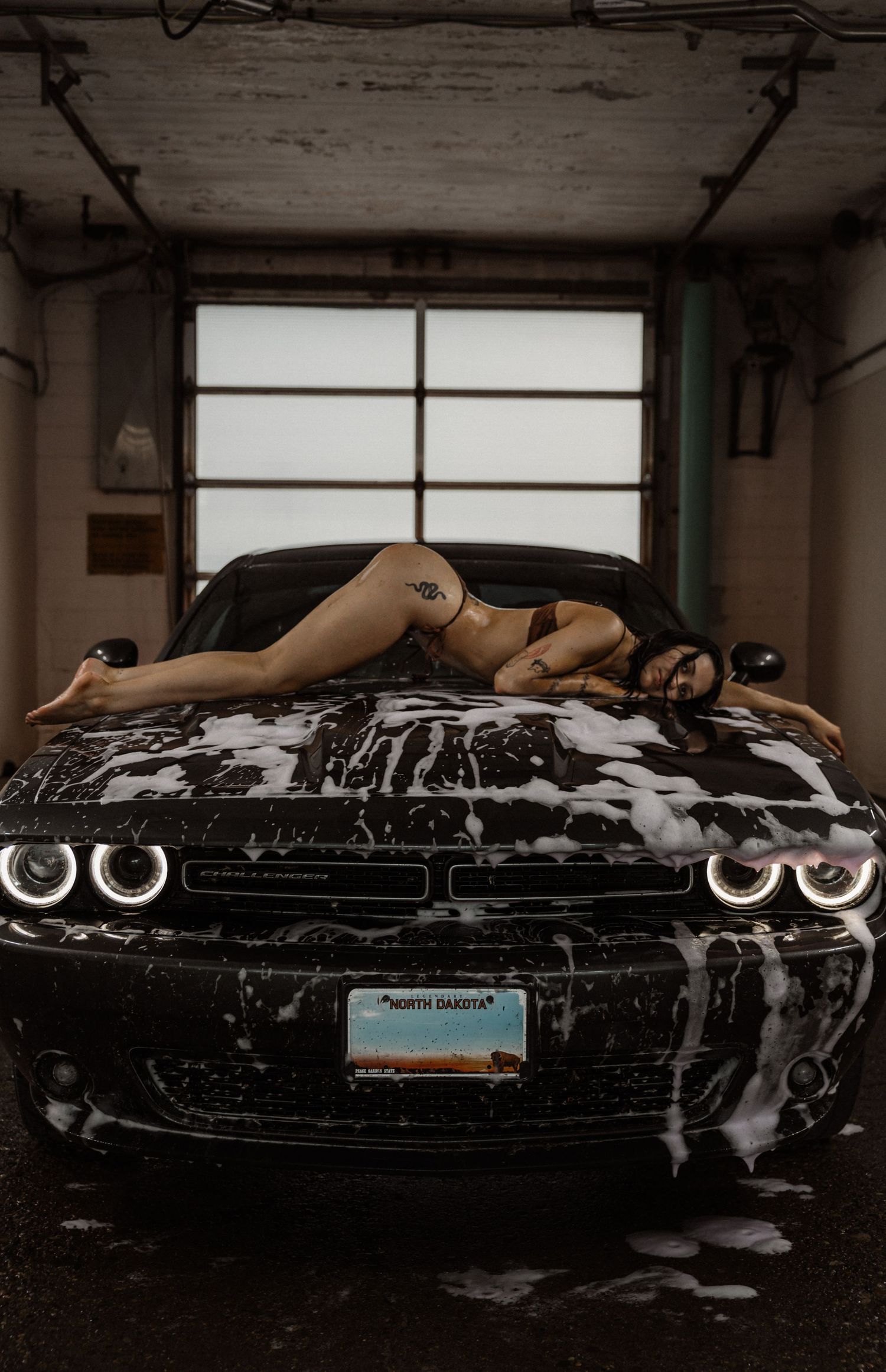Creative boudoir inspired portrait session at a car wash in Bismarck North Dakota featuring woman sitting on top of a car