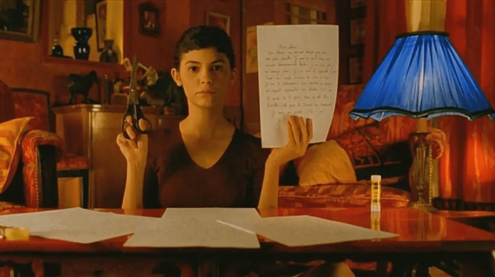 Student studying at desk with blue lamp and papers in warm-lit room.