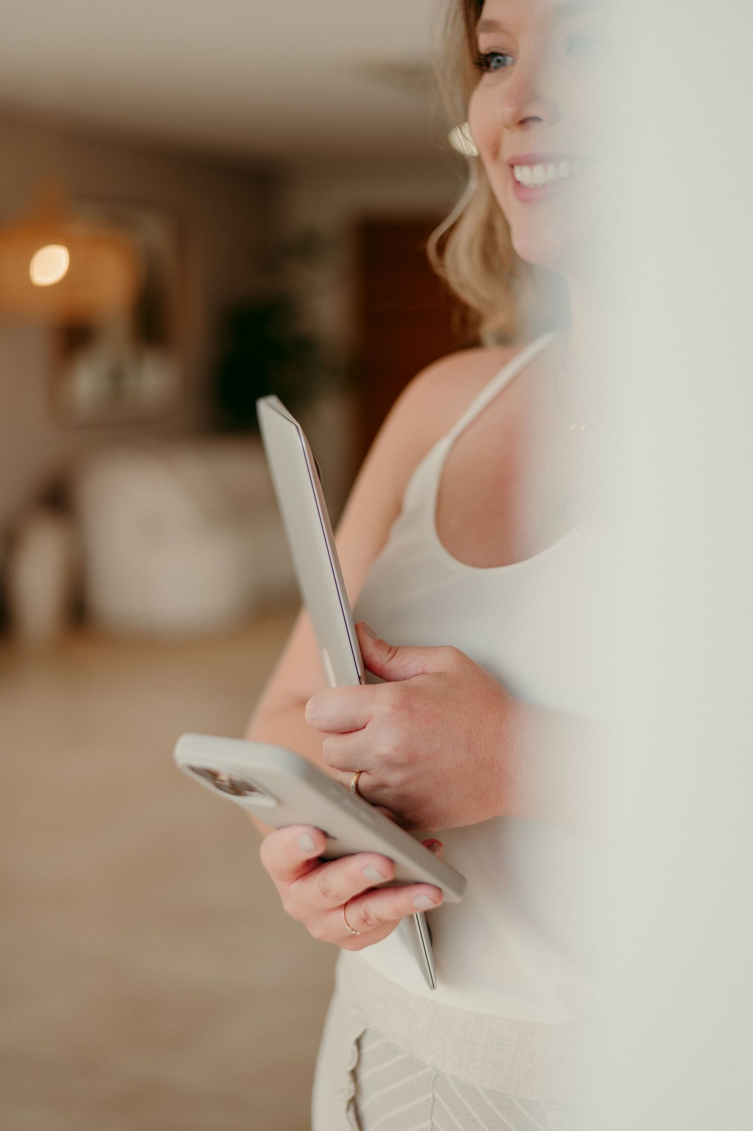 Woman in casual attire using mobile phone in bright modern interior setting.