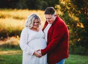 A couple in red and white attire share intimate moments during their golden hour outdoor photo session.