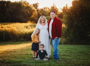 Family enjoying a golden sunset together in a grassy field during an outdoor autumn photoshoot.