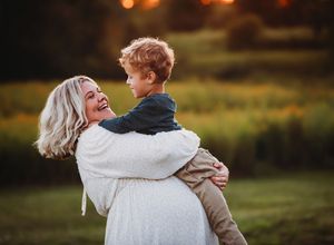 A couple embraces and dances together in a sunlit meadow during golden hour.