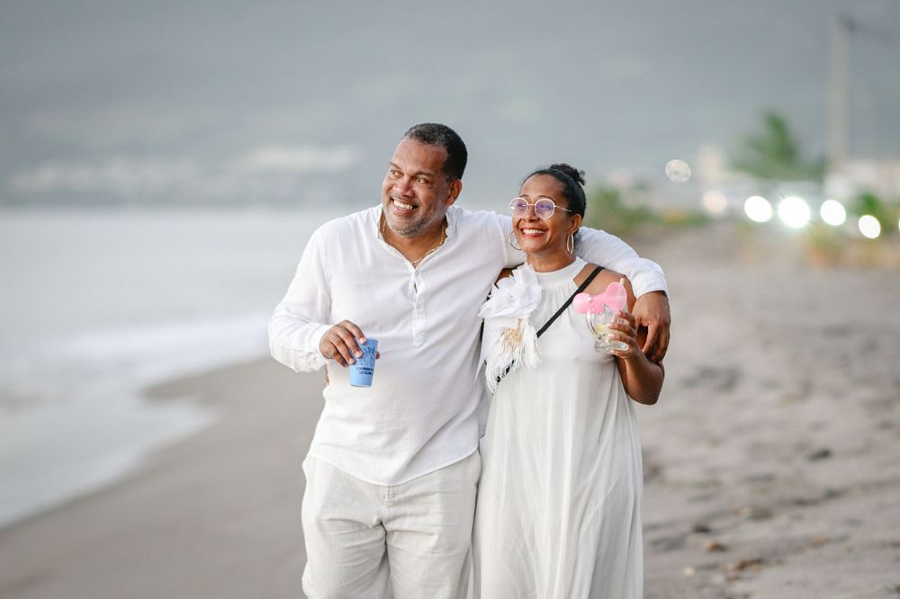 Couple heureux et souriant tous les deux en blancs sur une plage en Martinique