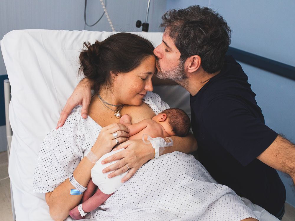 Intimate family moment on white bedding in natural light.