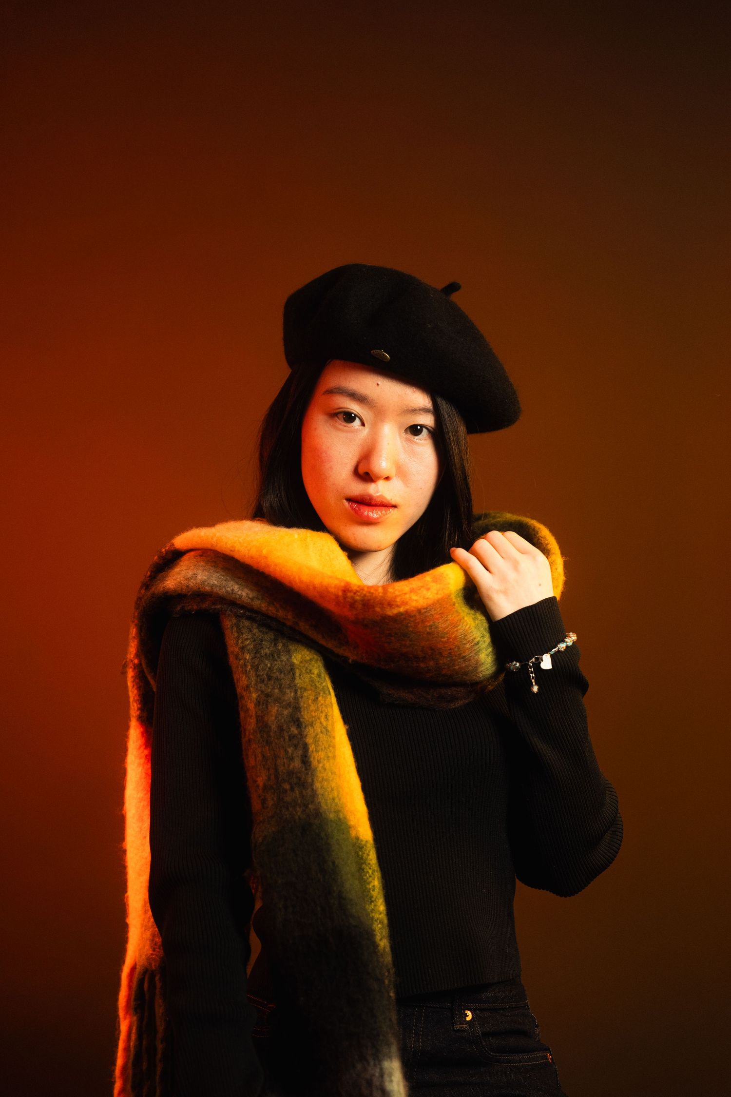 Moody portrait in warm lighting with black beret and scarf.