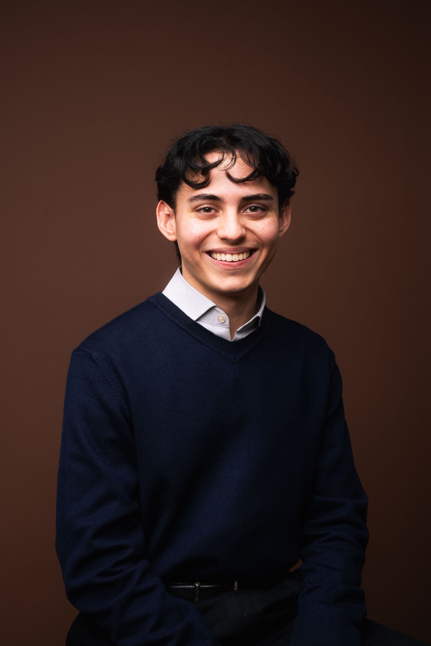 Professional studio portrait series showing a person in a navy sweater against a dark brown background.